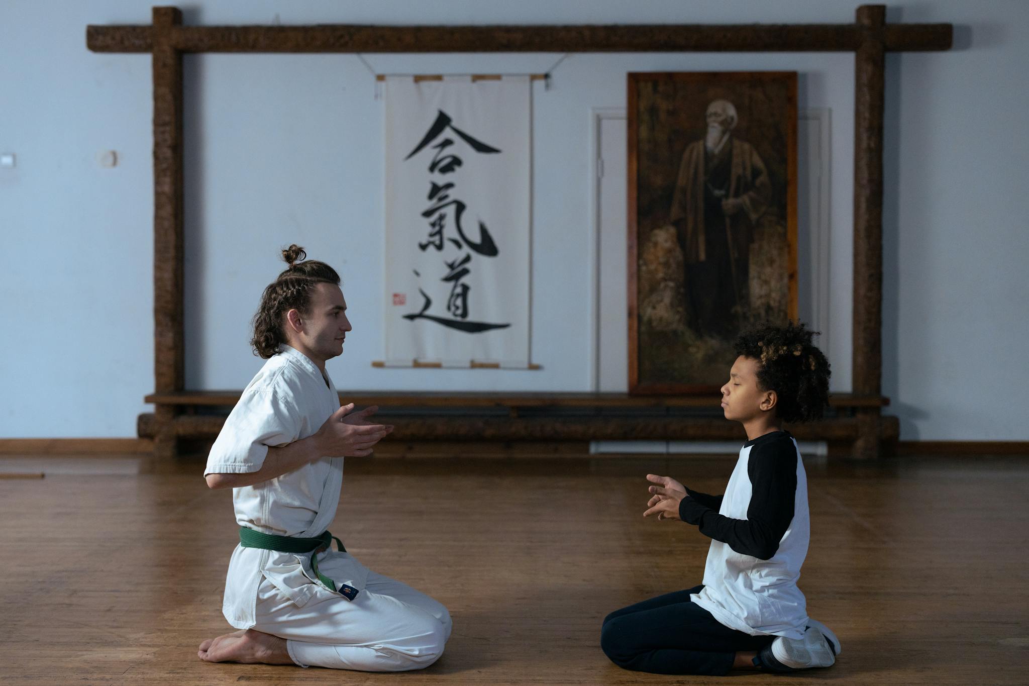 A man and child meditating in a dojo, focusing on martial arts discipline.